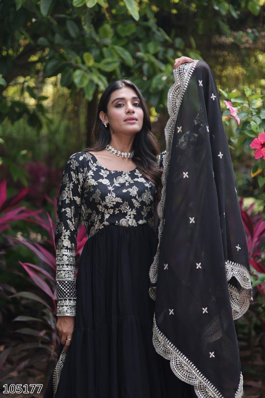 Woman holding a black embroidered dupatta against a green leafy background