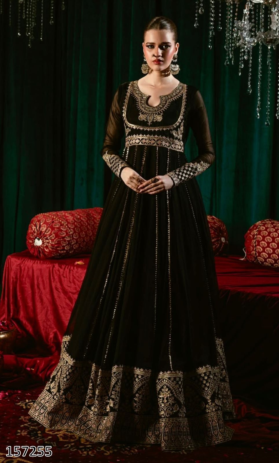 Woman in a black embroidered dress standing in a decorated room with red and green elements.