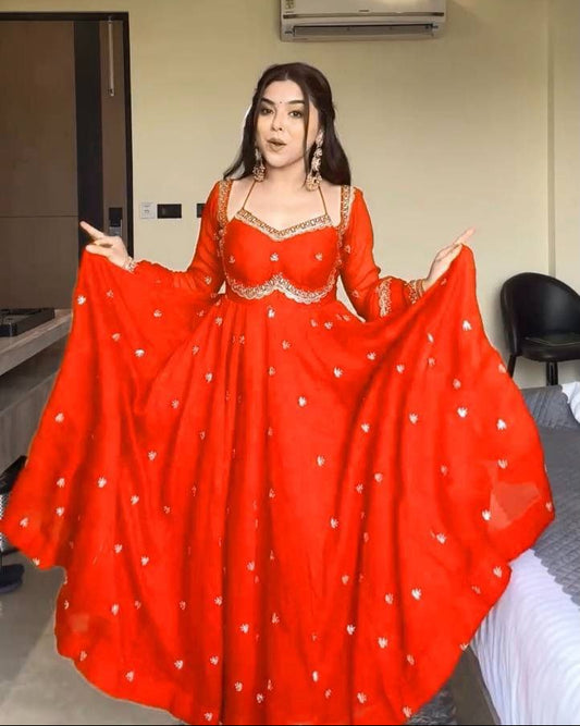 Woman in a red traditional outfit standing in a room with a ceiling fan and air conditioner.
