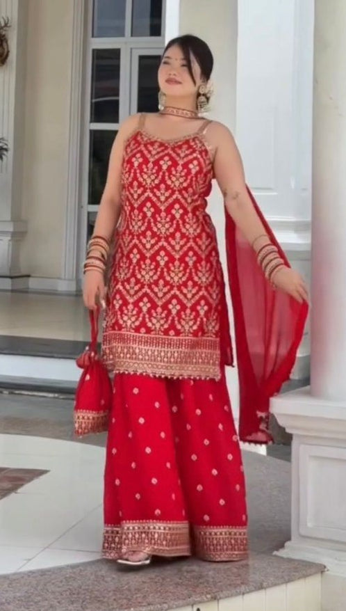 Woman in a red traditional outfit standing in a well-decorated indoor setting.