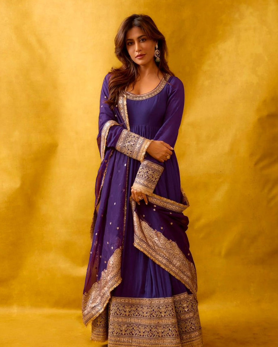 Woman in a purple and gold traditional outfit against a yellow background