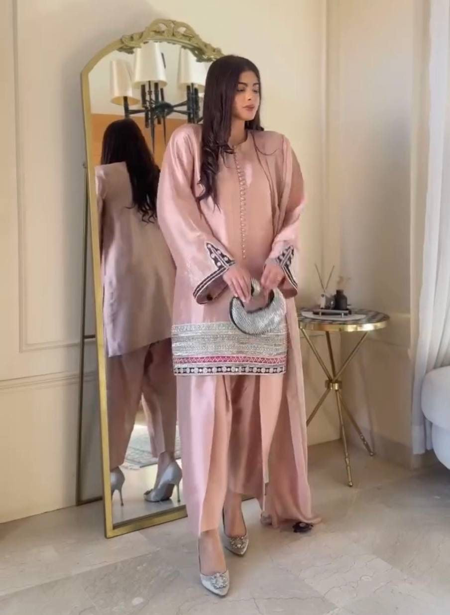 Woman in a pink dress standing in front of a mirror in an elegant room.