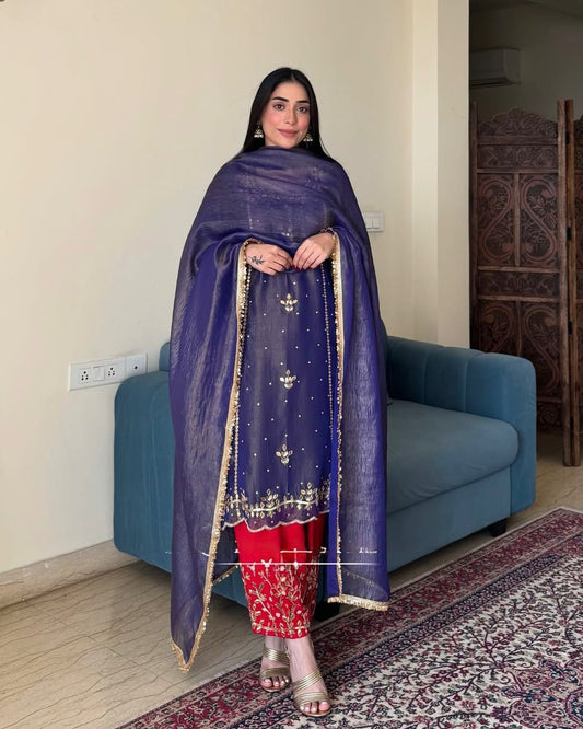 Woman wearing a blue dupatta with gold embroidery in a living room.