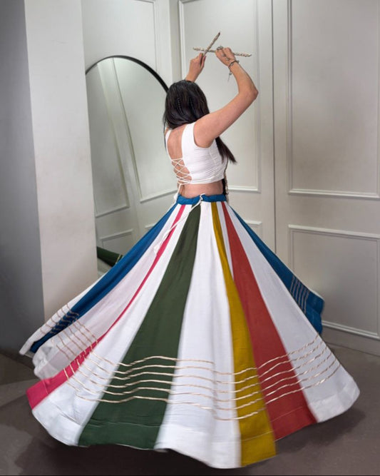 Woman wearing a colorful skirt with a white top, standing in front of a mirror.