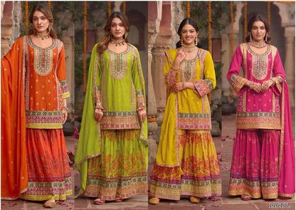 Four women wearing colorful traditional outfits with intricate patterns in an outdoor setting.