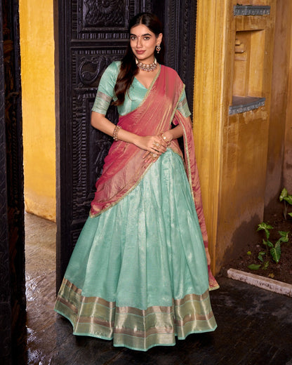 Woman in a traditional saree standing in front of a wooden door.