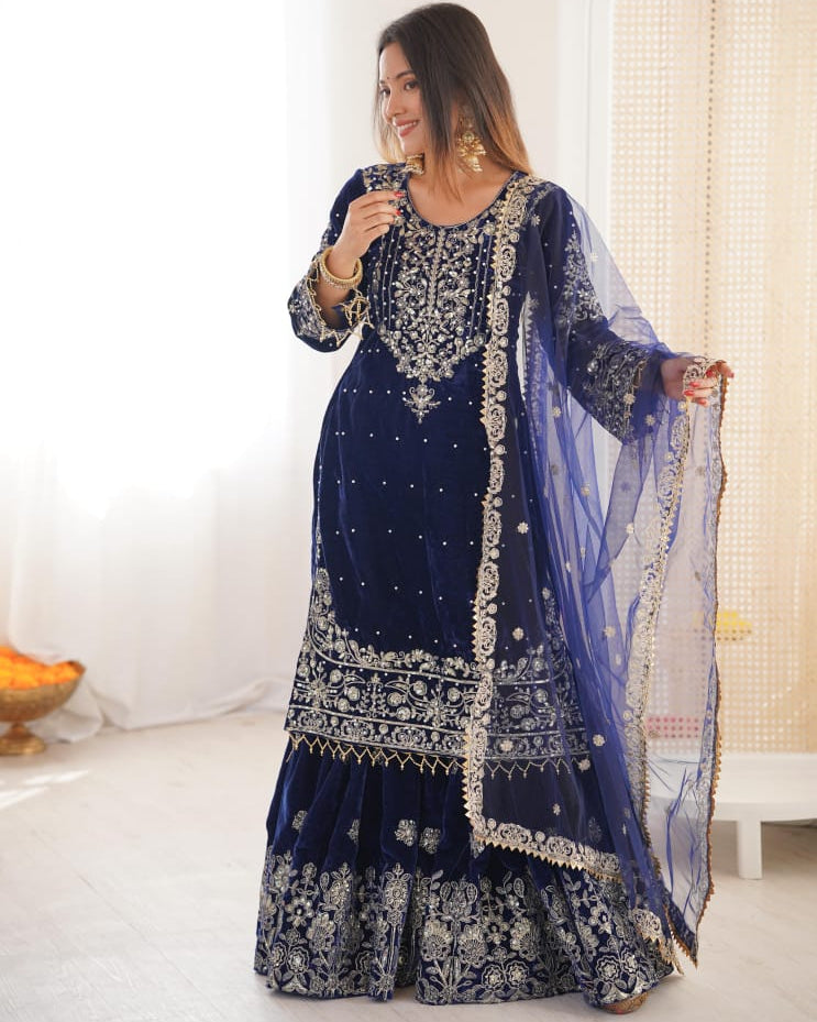 Woman wearing a traditional blue embroidered outfit with a white background