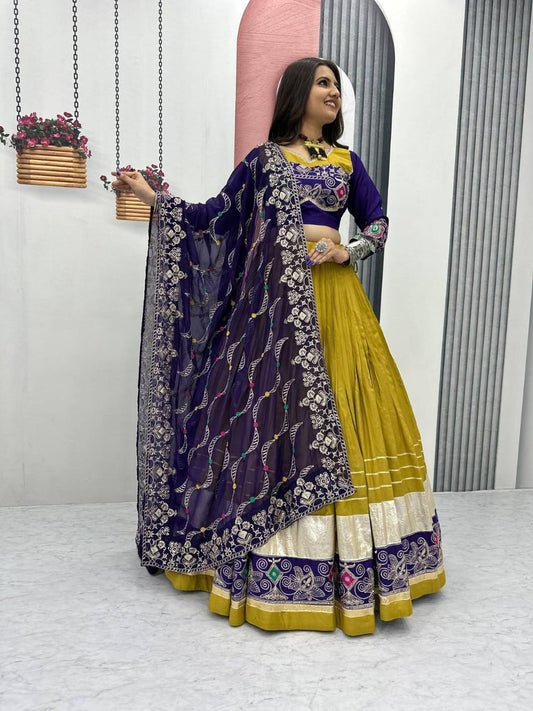 Woman in a traditional outfit with a purple and yellow dress, standing indoors.