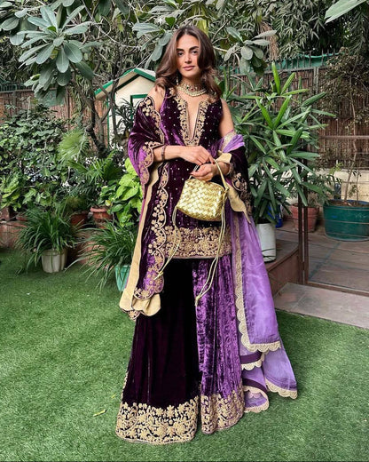 Woman in a purple and gold traditional outfit standing in a garden.