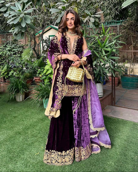 Woman in a purple and gold traditional outfit standing in a garden.