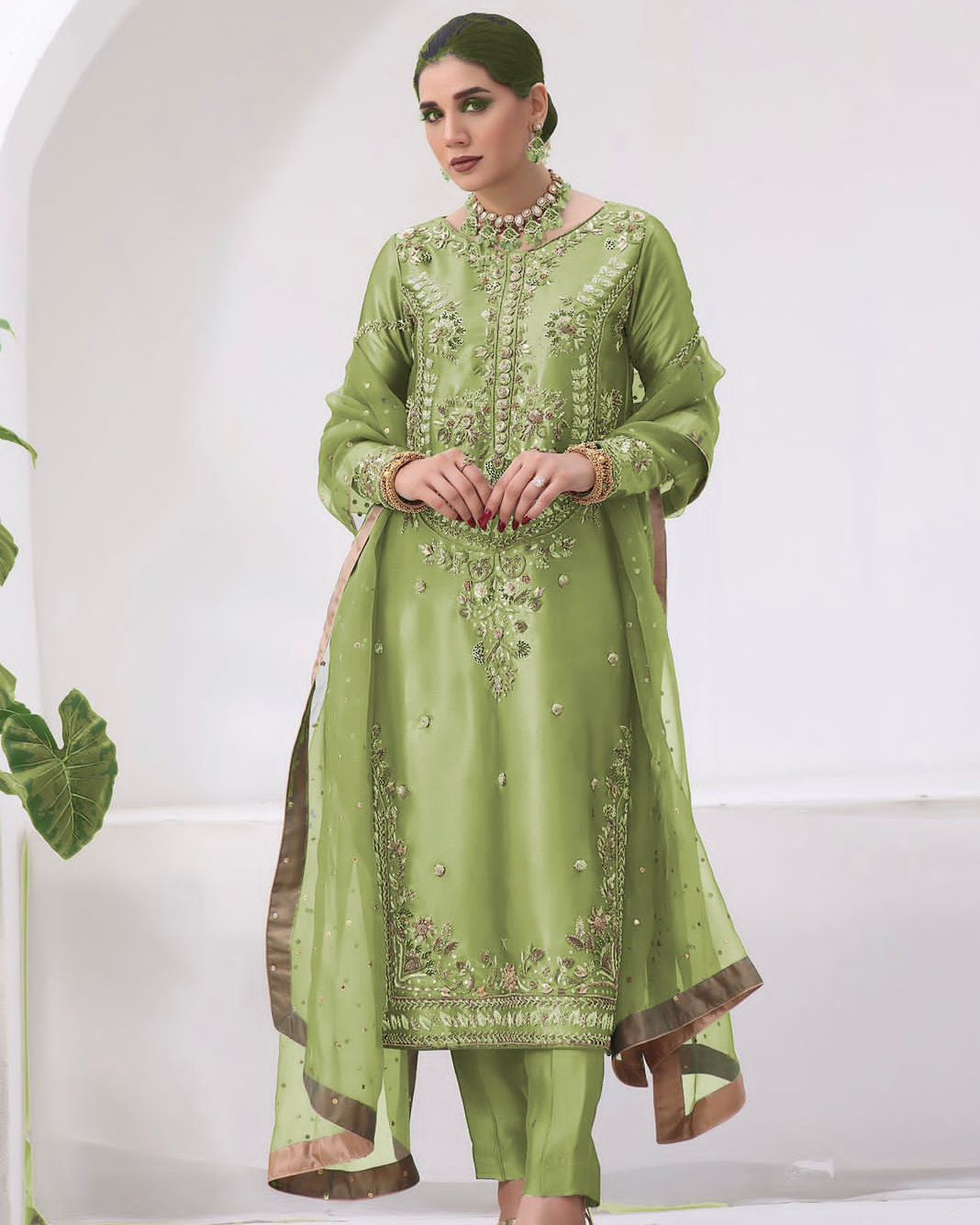 Woman wearing a green embroidered traditional outfit in a minimalistic setting