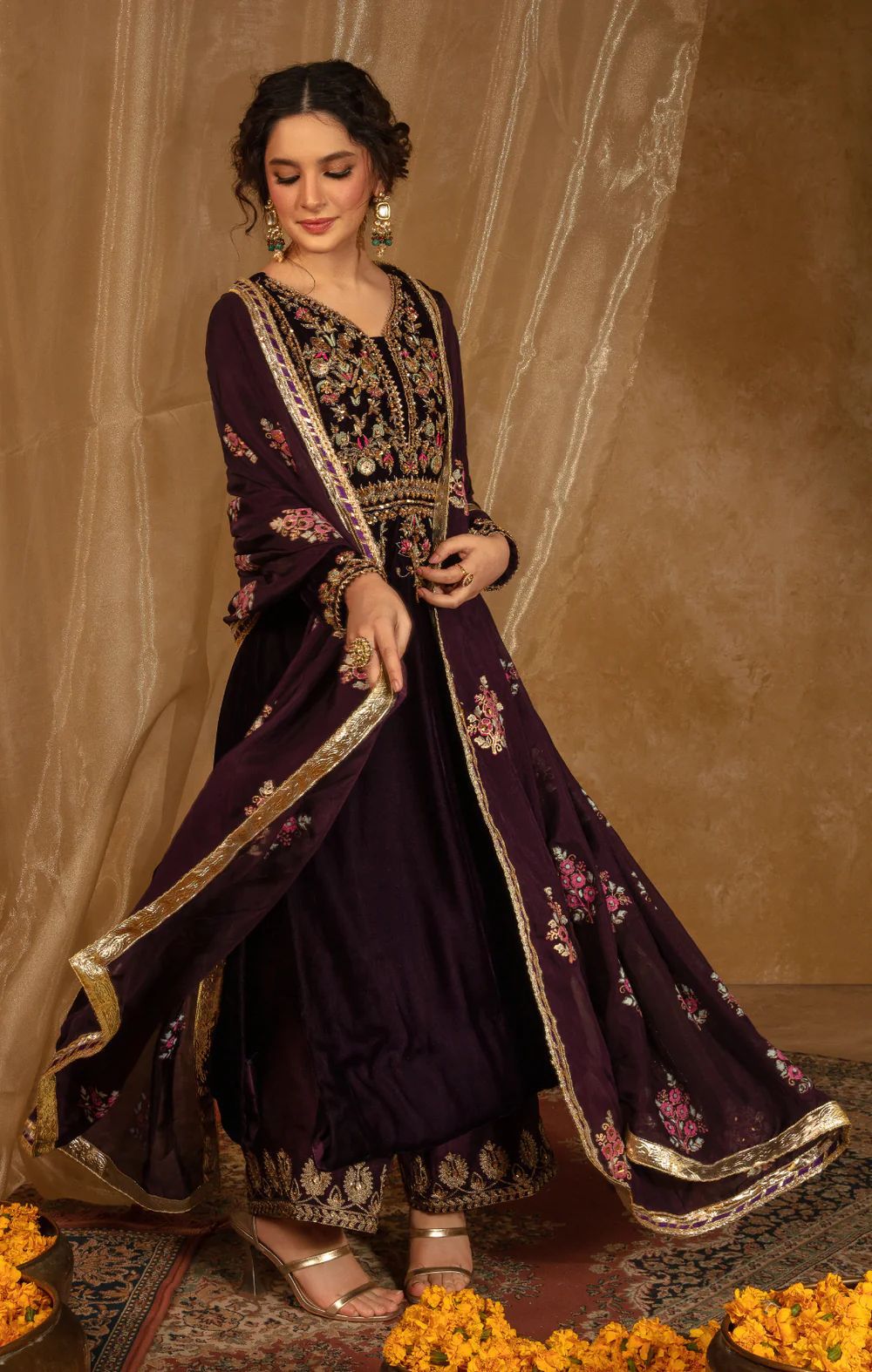 Woman in a dark purple traditional outfit with floral patterns on a beige background