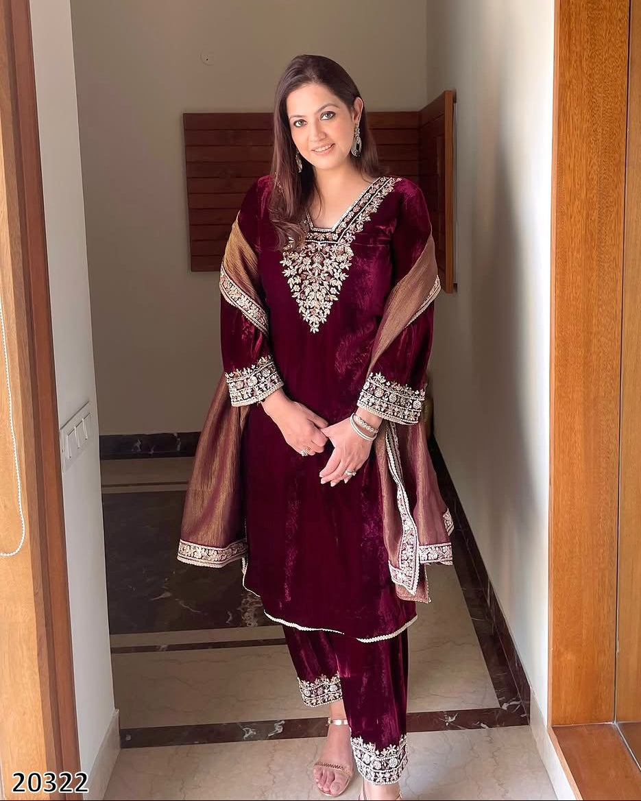 Woman wearing a maroon traditional outfit with silver embroidery in a room.