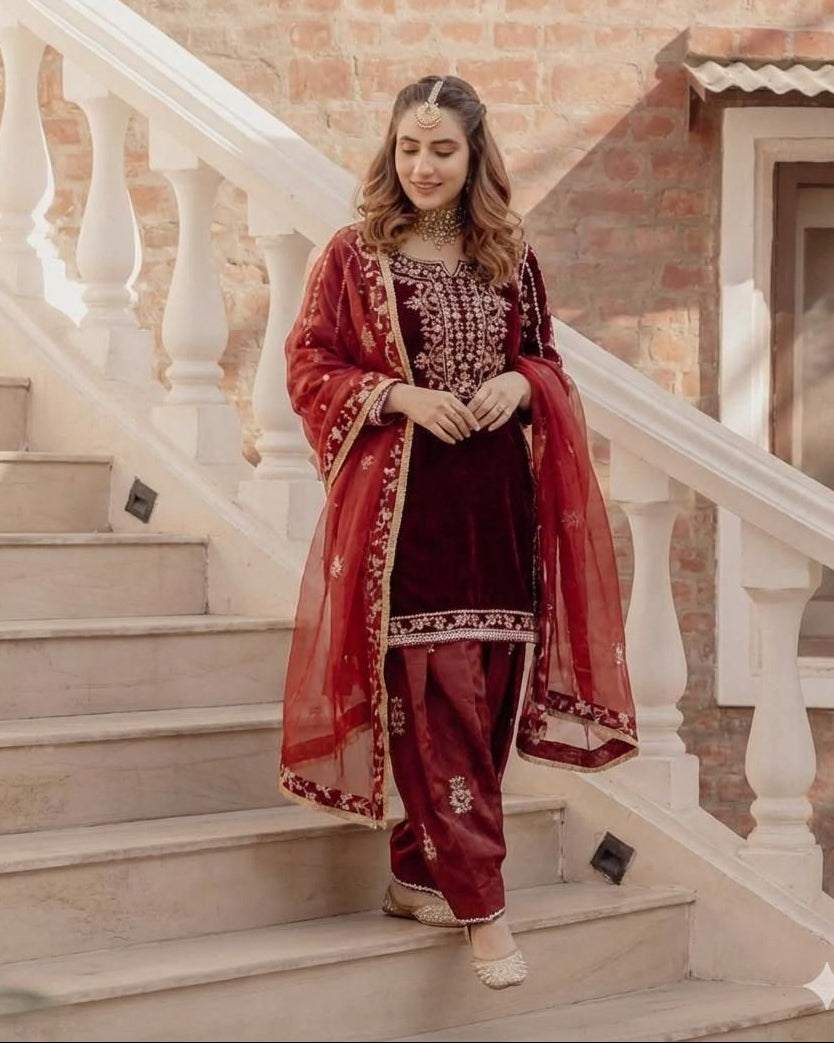 Woman in a red traditional outfit standing on a staircase with a brick wall background