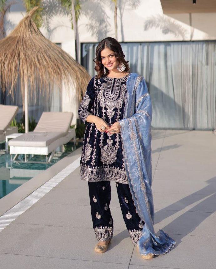 Woman in traditional outfit standing by a poolside with modern architecture in the background