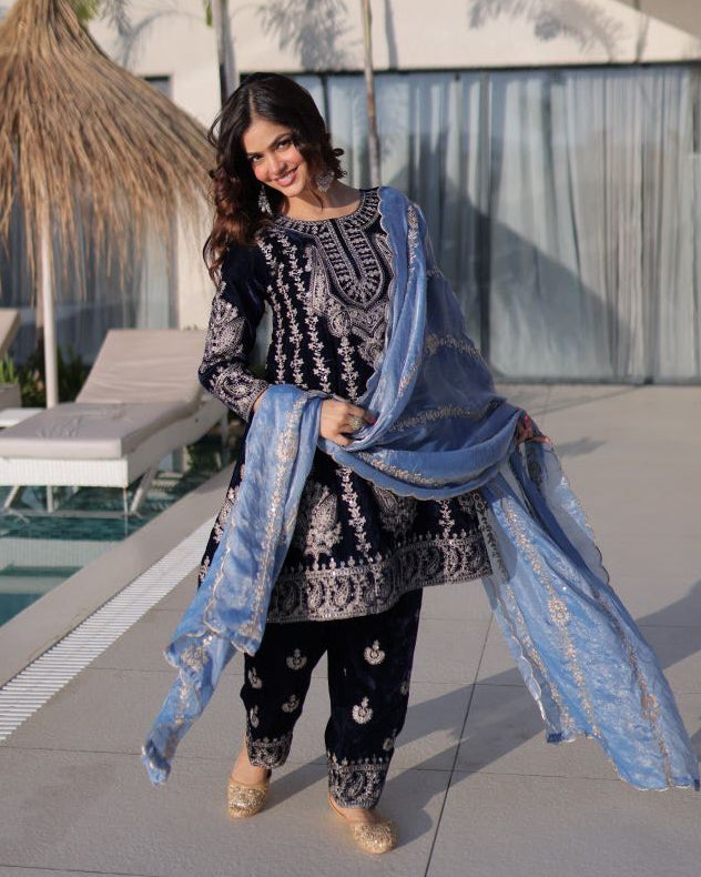 Woman in traditional outfit with a blue dupatta by a poolside.