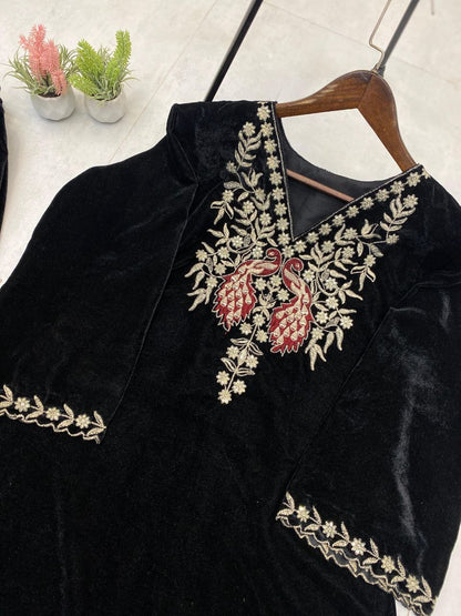 Black velvet blouse with intricate white and red embroidery on a hanger.
