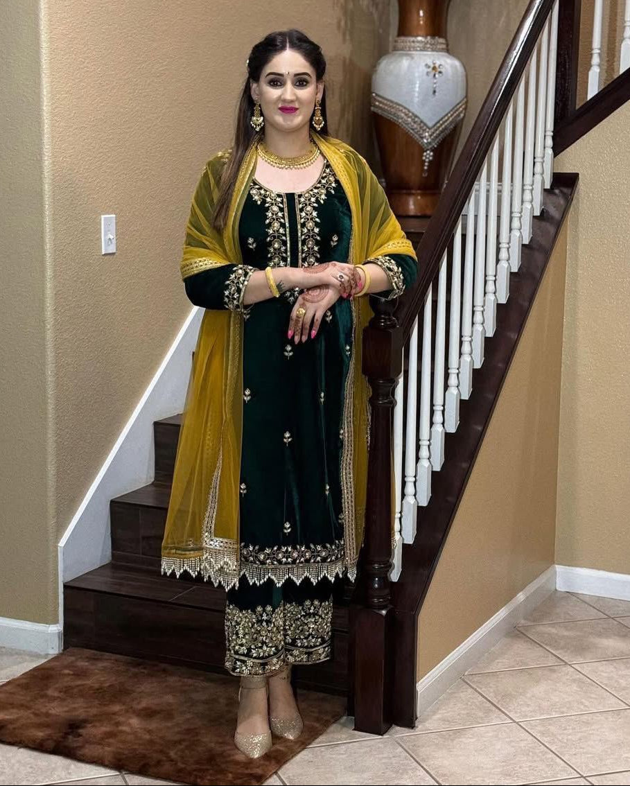 Woman in traditional green and yellow outfit standing in a home setting.