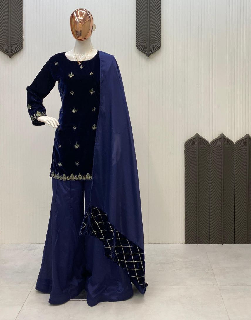Navy blue traditional outfit with a cape on a mannequin against a textured wall.